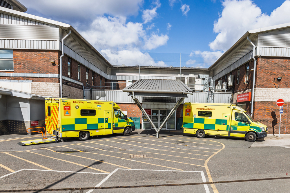 Two yellow ambulances parked outside a modern ambulance station building on a sunny day.//Depositphotos